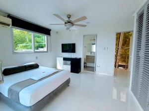 a white bedroom with a bed and a ceiling fan at Hotel Kaamú Taganga in Taganga