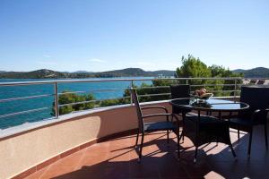 einen Tisch und Stühle auf einem Balkon mit Blick auf das Wasser in der Unterkunft Apartments Villa Leona in Betina