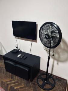 a black fan sitting on a table next to a television at Departamento ESPAÑA in Paraná