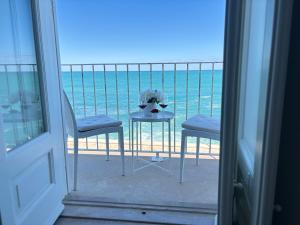 a table and chairs on a balcony with the ocean at Antica Dimora sul Mare - Elegant Central Apartments - Molfetta in Molfetta
