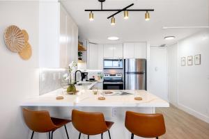 a kitchen with a large white island with orange chairs at Ilikai Marina Stunning Ocean & Harbor Views - Walk to the Beach! in Honolulu