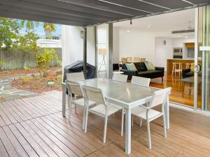 a white dining room table and chairs on a deck at Maggies Beachfront Apartment 2 in Horseshoe Bay