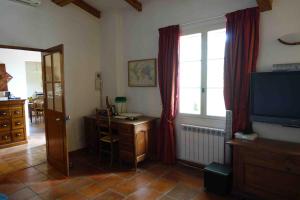 ein Wohnzimmer mit einem TV, einem Schreibtisch und einem Fenster in der Unterkunft L'Enclos in Aix-en-Provence