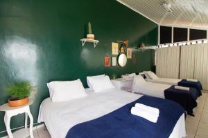 a bedroom with two beds and a green wall at Happiness House Hospedagem in Cuiabá