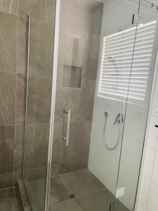 a bathroom with a shower with a glass door at Living Oasis Home in Auckland