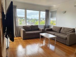 a living room with two couches and a table at Living Oasis Home in Auckland