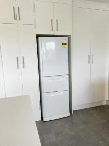 a white refrigerator in a kitchen with white cabinets at Living Oasis Home in Auckland