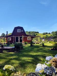 a red house with a green yard with flowers at Pousada Rancho do Lago in Osório