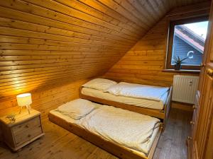 two beds in a wooden room with a window at Feriendorf Blauvogel Blauvogel 040 in Hasselfelde