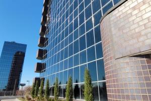 a tall glass building with trees in front of it at Peaceful Midtown Apartment with Gym and Parking in Tulsa