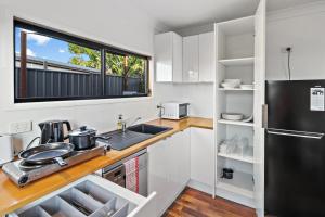 a kitchen with a sink and a black refrigerator at Wine Country Cottage in Cessnock