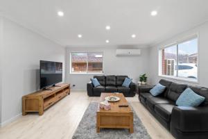 a living room with a couch and a tv at Budge near the Beach in Budgewoi