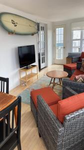 un salon avec une télévision et une planche de surf murale dans l'établissement Ocean Block, Wifi, Beach Badges, Ship Bottom, à Ship Bottom