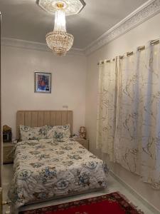 um quarto com uma cama e um lustre em Marrakech héberg em Marraquexe