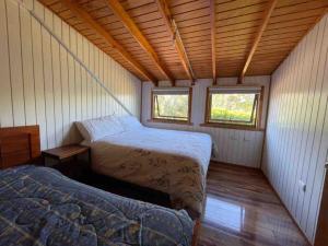 a bedroom with two beds in a wooden house at Cheerful Santa Juana Cabin in Santa Juana