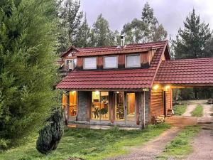 a house with a red roof on a yard at Cheerful Santa Juana Cabin in Santa Juana