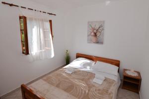 a bed in a white room with a window at Secluded fisherman's cottage Cove Zizanj, Pasman - 23925 in Tkon