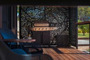 a grill on a screened in porch with chairs at ARBY - Irvine Wines Tiny Home in Craneford