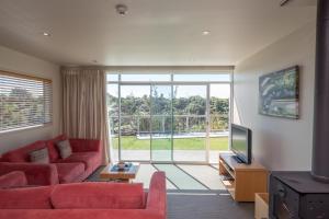 a living room with a red couch and a television at One Burgess Hill in New Plymouth
