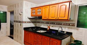 サン・ヒルにあるApartamento Turístico JKのキッチン(オレンジ色のキャビネット、黒いカウンタートップ付)