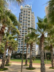 a group of palm trees in front of a tall building at Lovely 3 Bedroom Mini Penthouse on 30th Floor in Netanya