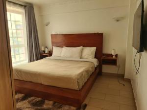 a bedroom with a bed and a window and a television at Skyline Dream Homes 4, 6 in Nairobi