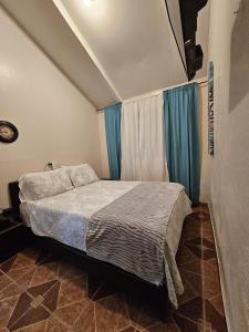 a bedroom with a bed and blue curtains at Lovely Flower Garden Apartment in Alto Boquete