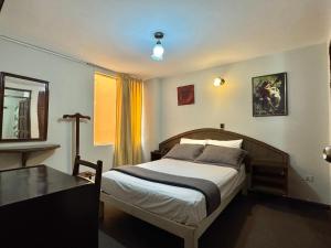 a bedroom with a bed and a table and a mirror at Hotel Los Angeles in Arequipa