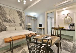 a bedroom with a bed and a table and chairs at February Hotel Gimhae in Gimhae