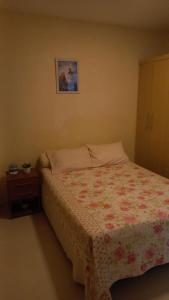 a bedroom with a bed with a floral bedspread on it at Casa - Aluguel por temporada in Garanhuns