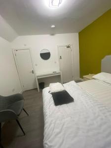 a bedroom with a bed and a chair and a desk at Heathrow Close Comfort Room in Stanwell
