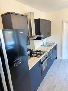 a kitchen with blue cabinets and a refrigerator at Heathrow Close Comfort Room in Stanwell