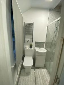 a white bathroom with a toilet and a sink at Heathrow Close Comfort Room in Stanwell