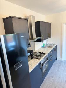 a kitchen with a refrigerator and a stove top oven at Heathrow Close Comfort Room in Stanwell