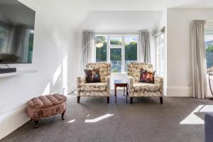 a living room with two chairs and a table and a window at Grand 5-Bedroom Villa in Fendalton in Christchurch