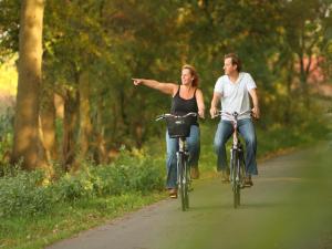 a man and a woman riding bikes down a road at Holiday Home in Netherlands with Private Garden in Plasmolen
