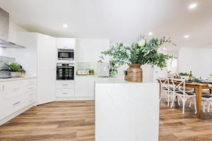 a kitchen with white cabinets and a table with a vase of flowers at Ocean Haze - Prime Beachfront Getaway in Agnes Water