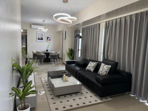 a living room with a black couch and a table at 175 Sqm Luxurious Modern 3 Bedrooms Facing Manila Bay Sunset, Airports, Okada, Solaire, MOA in Manila