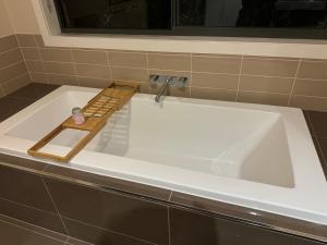 a white bath tub with a wooden tray on it at Cozy family home near suft coast 6 beds in Grovedale