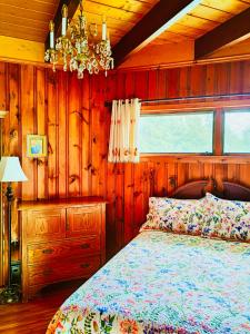 a bedroom with a bed and a chandelier at Knotty Pines Oceanside Inn in Peggy's Cove