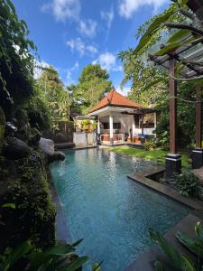 a swimming pool in front of a house at Bumbung Sari Villa in Ubud