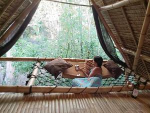 a woman sitting on a bed in a forest at Ecocio Explorations in Coron