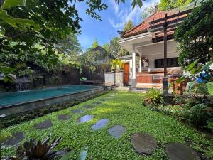 a backyard with a swimming pool and a house at Bumbung Sari Villa in Ubud