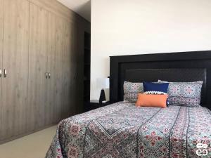 a bedroom with a large bed with an orange pillow at Departamento con alberca, a 4 cuadras de playa - L8 in La Florida