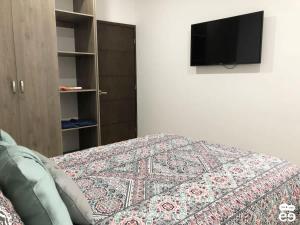 a bedroom with a bed and a tv on a wall at Departamento con alberca, a 4 cuadras de playa - L8 in La Florida +13 photos