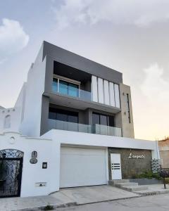a white building with a garage in front of it at Departamento con alberca, a 4 cuadras de playa - L8 in La Florida