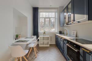 a kitchen with a sink and a counter with chairs at Brand New Luxury Apartment, Parking, Center in Vilnius