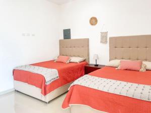 a bedroom with two beds with red and white sheets at Bello Departamento a 3 cuadras de la playa - Flaminguito in Mazatlán