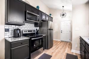 eine Küche mit schwarzen Schränken und einem Herd mit Backofen in der Unterkunft Serenity Cottage 300mbps Wifi - Dog Friendly in Clarksville + 10 Fotos
