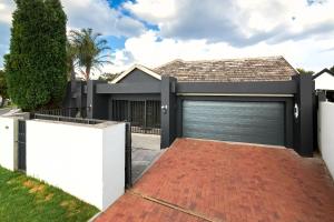 a garage door in a house with a brick driveway at Private, Cosy and Stylish Stay at Nest24 Evans Park in Johannesburg